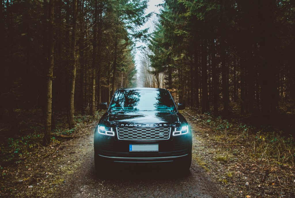 Voiture Range Rover noir sur une route de forêt