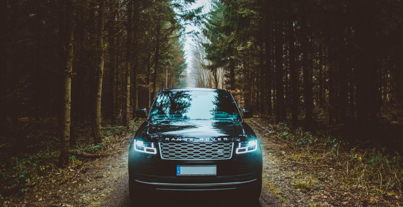 Voiture Range Rover noir sur une route de forêt